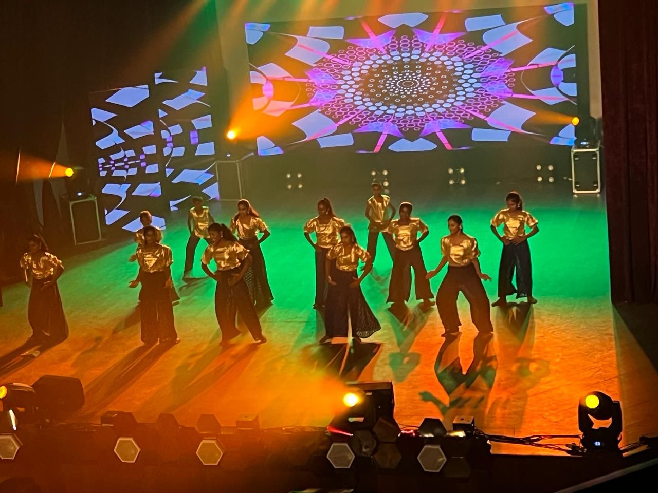 Dance group in gold tops on a lit stage during a performance