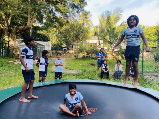Home of Hope children in sports shirts on and around the garden trampoline