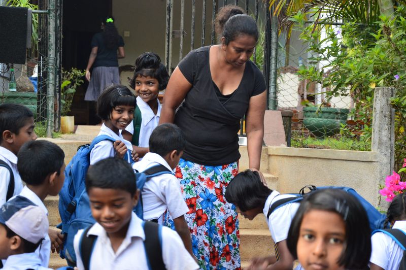 Sharmini zwaait de kinderen uit naar school